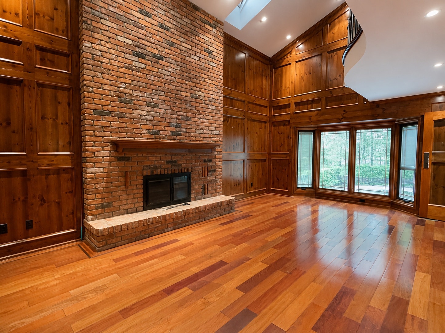 A completely empty, sunlit living room with vaulted ceilings and a brick fireplace, ready for staging