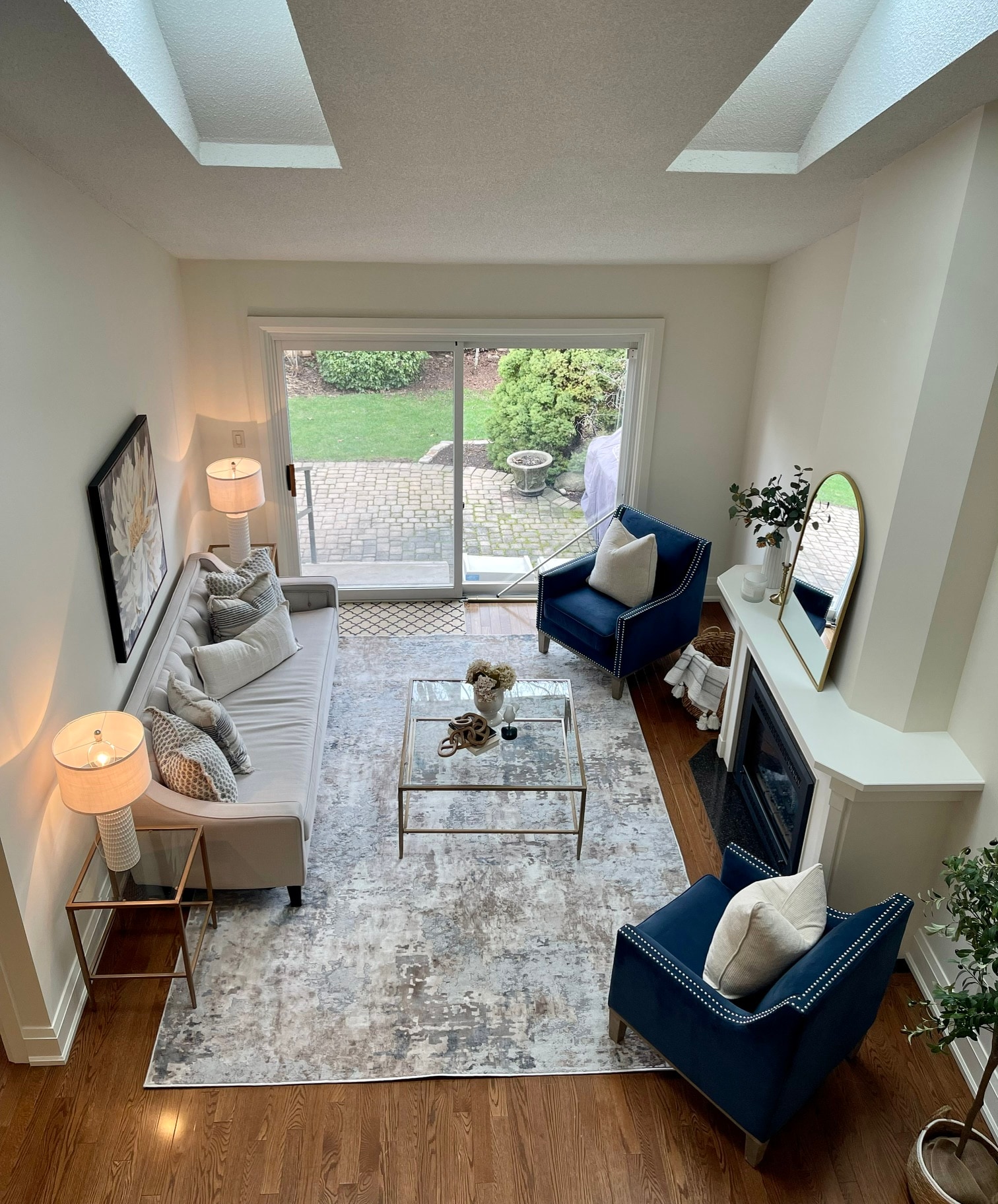 Same living room after staging, with navy accent chairs and a grey sofa