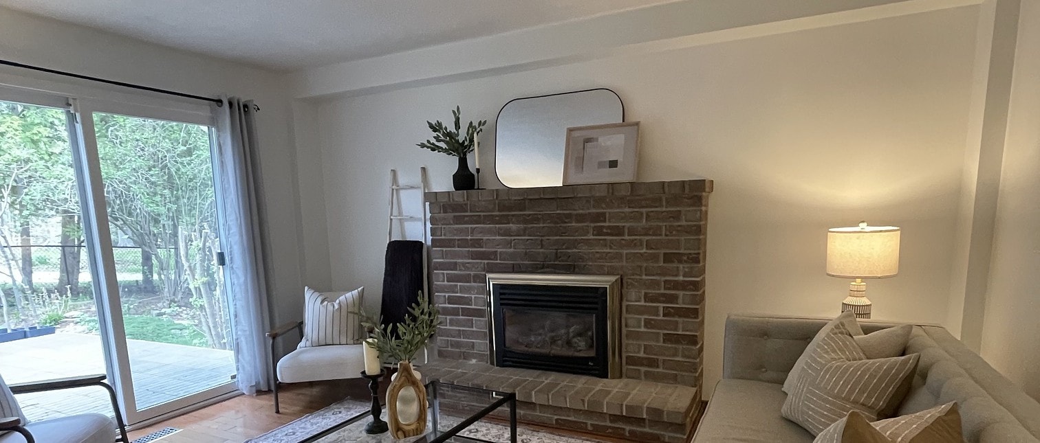 Staged living room with a brick fireplace, mirror, and cozy seating